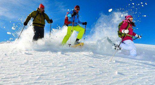 Drei Personen in Winterkleidung betreiben Schneeschuhwandern in Reit im Winkl