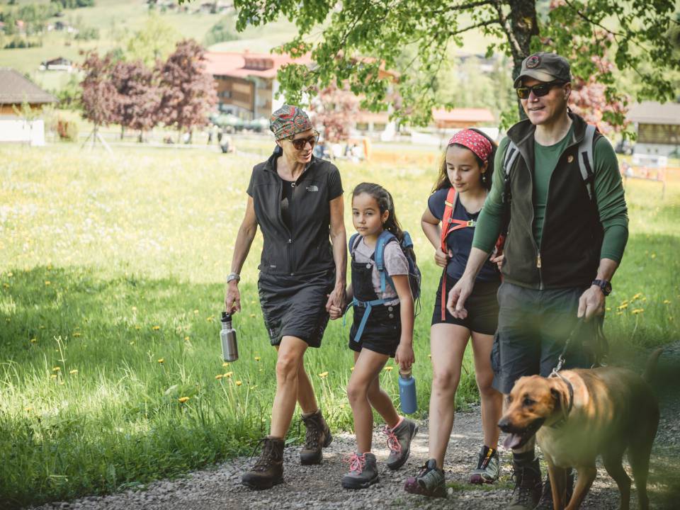 Ein Mann, eine Frau, zwei Mädchen und ein Hund auf ihrem Weg zum Wandern im Sommerurlaub in Bayern