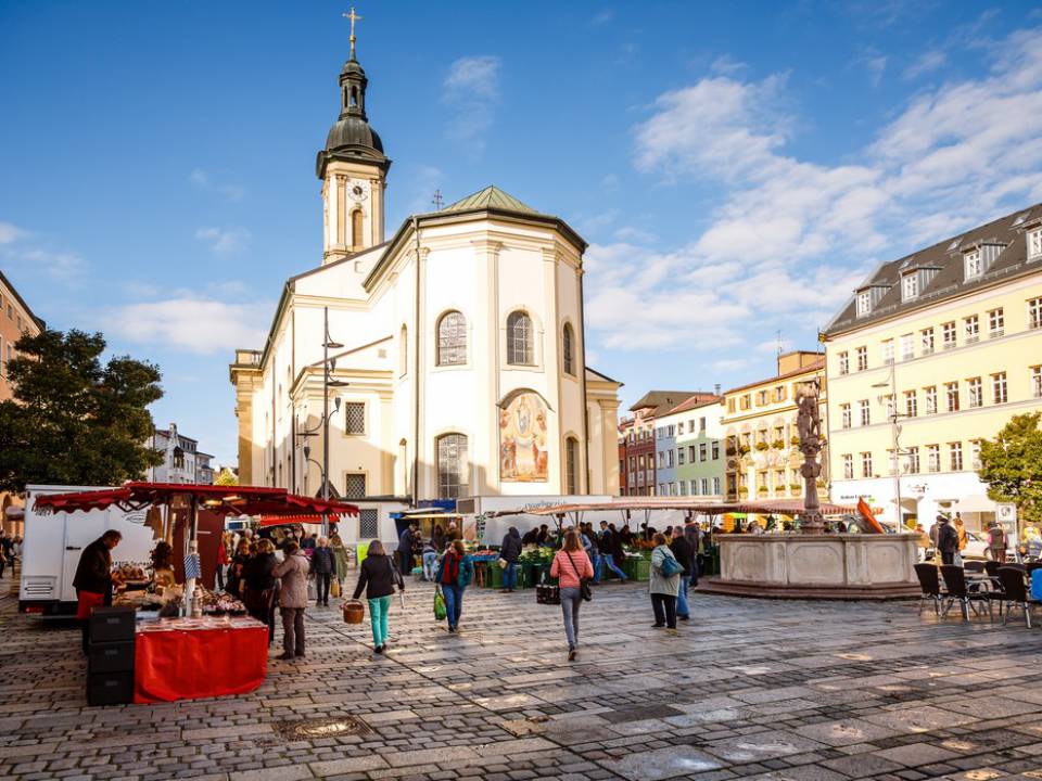 Menschen auf dem Hauptplatz vor einer Kirche in Traunstein