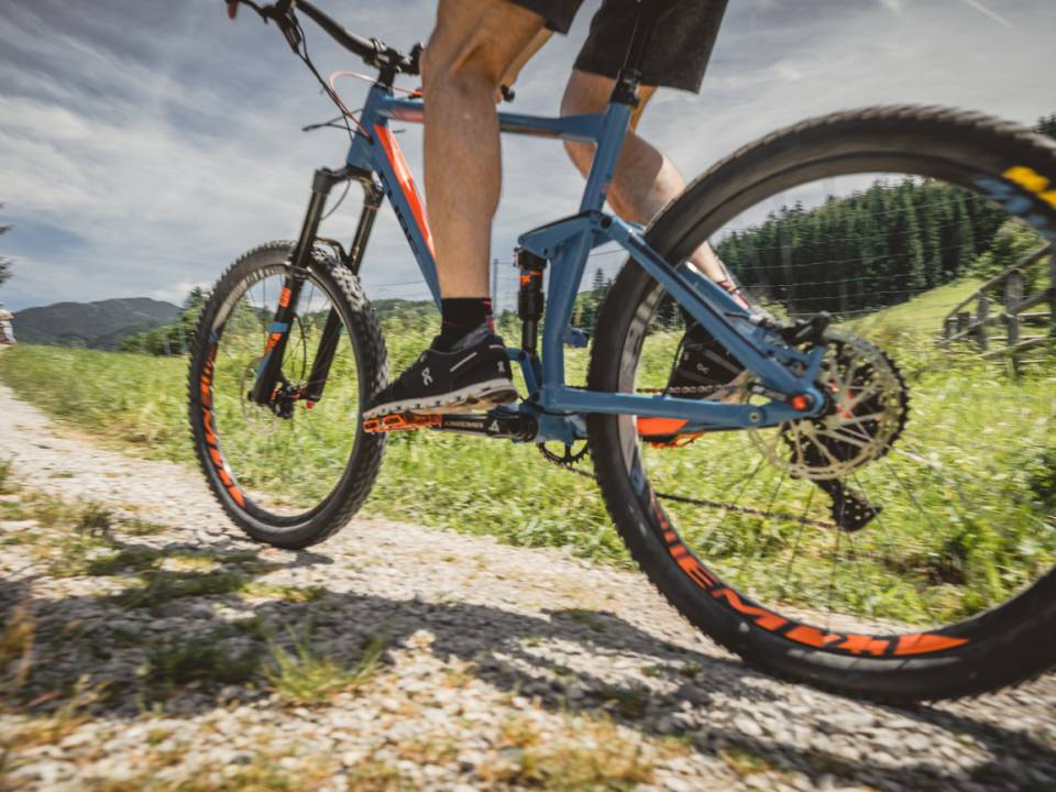 Fahrradfahrer fährt auf einem blauen Mountainbike einen schmalen Kiesweg hoch