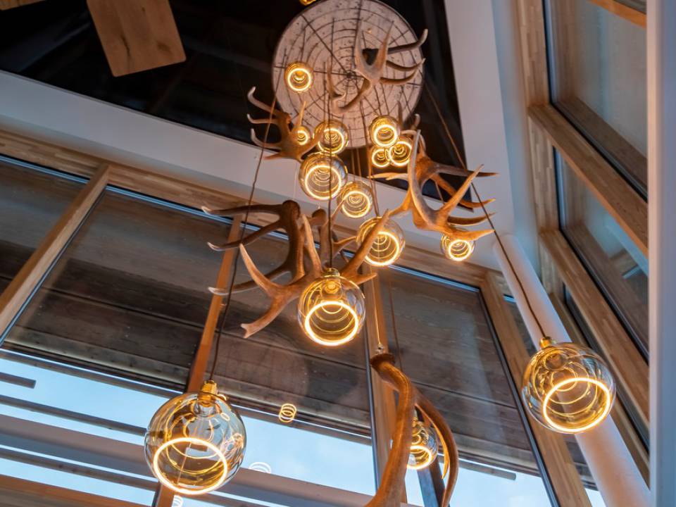 Aufnahme von unten nach oben auf eine hängende Lampe mit Geweihen und Glühbirnen